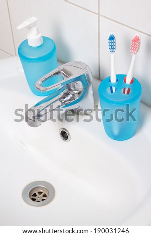 close up of toothbrushes and soap on white sink