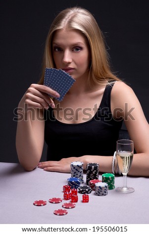 young beautiful blond woman playing poker in dark room