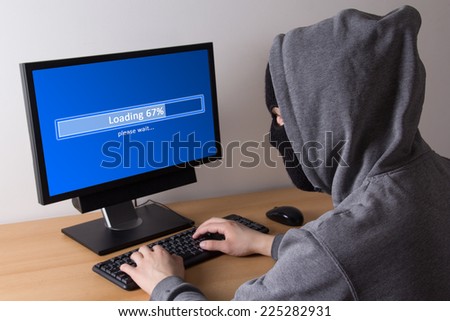 male thief in mask stealing data from computer