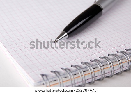 spiral note book with checked pages and pen