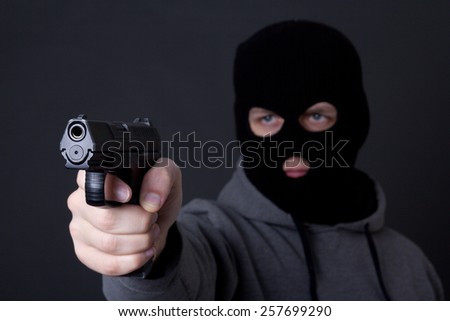 man in black mask aiming with gun over grey background