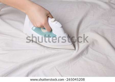 iron in female hand ironing wrinkled cotton linen