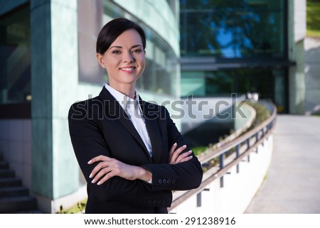 business concept - young beautiful woman in suit over modern city background