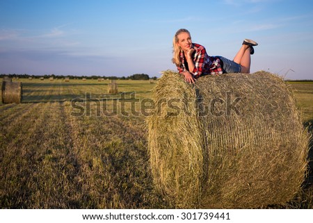 country concept - young beautiful romantic woman lying on haystack in field