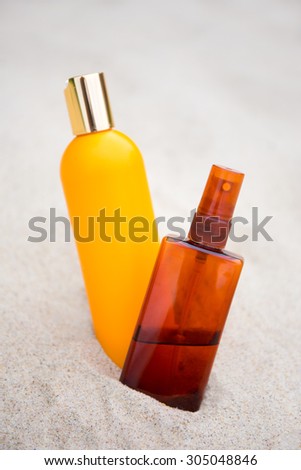 sunbathing concept - close up of suntan lotion bottles in sand