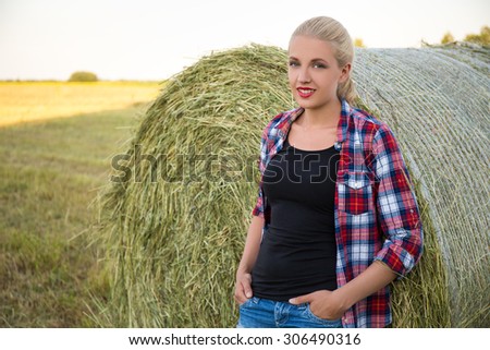 young beautiful blonde woman in field with haystacks