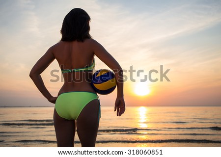 back view of slim sexy woman in bikini with ball over sea background