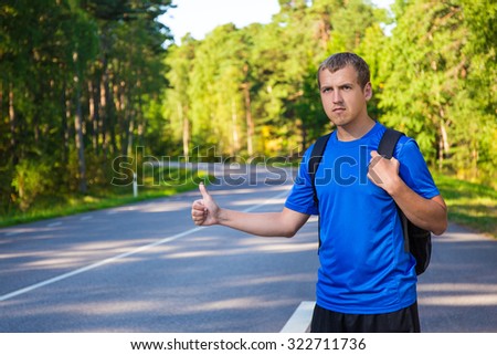 young hitchhiking traveler try to stop car on forest road
