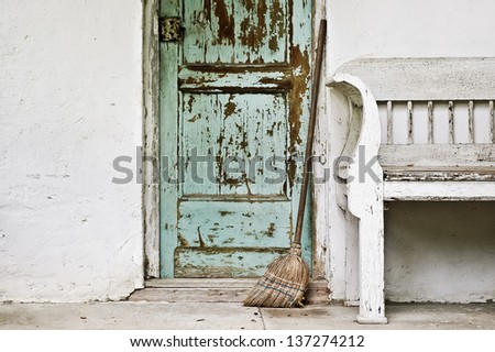 Rural mood: Green door, white wall an old bench, broom
