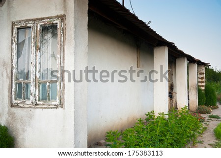 Old run down gipsy wooden windowed adobe farm house yard with some summer flowers