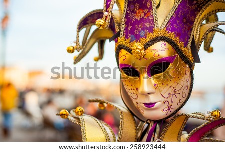 Beautifully painted ornate golden venetian mask hanging ob blurred background