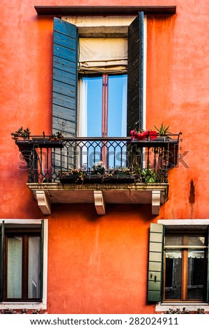 Old venetian building colorful painted facade with balcony window decorated with plants