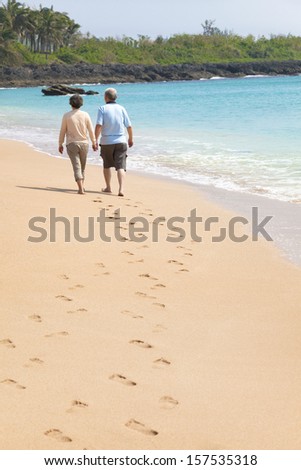 happy senior walking on the beach with footprint