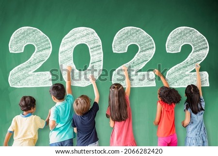 School children drawing 2022 new year on the chalkboard.