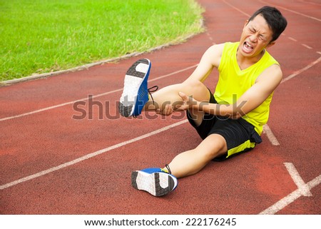 young male runner suffering from leg cramp on the track in the stadium