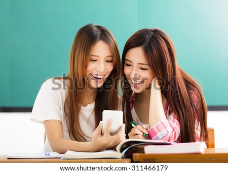 happy students girls watching the smart phone in classroom