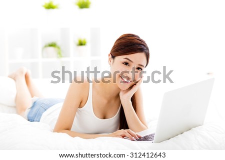 smiling young woman with laptop on the bed