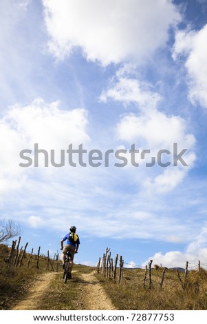 Young man riding mountain bike and watching cloudy sky