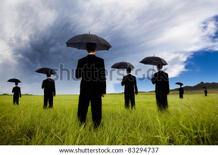 businessman in black suit  holding umbrella and watching the storm coming