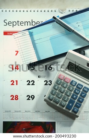 Calendar, checkbook, calculator, money and a ballpen Photo of a calendar, checkbook, calculator, money and a ballpen