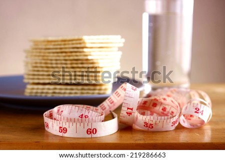 Soda Crackers, Glass of water and a measuring tape Photo of a stack of soda crackers, glass of water and a measuring tape