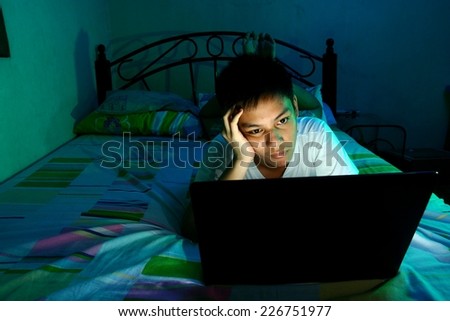 Young Teen in front of a laptop computer and on a bed Photo of a Young Teen in front of a laptop computer and on a bed