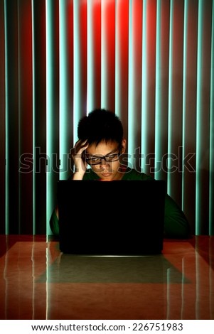 Young Teen with eyeglasses and his eyes closed in front of a laptop computer Photo of a Young Teen with eyeglasses and his eyes closed in front of a laptop computer