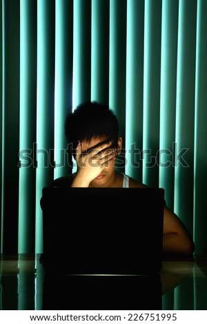 Young Teen in front of a laptop computer and covering his eyes Photo of a Young Teen in front of a laptop computer and covering his eyes