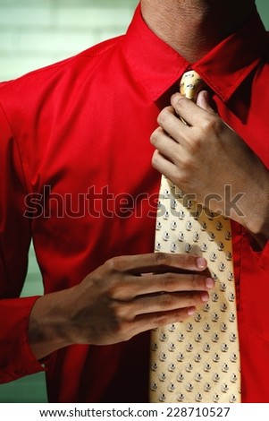 Man wearing red long sleeve shirt and yellow necktie Photo of a man wearing red long sleeve polo shirt and holding his yellow necktie