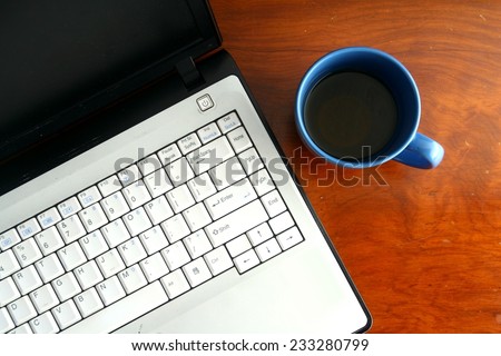 Laptop computer and a blue coffee mug on a table Photo of a Laptop computer and a blue coffee mug on a table