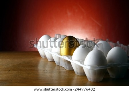 one golden among ordinary eggs in an egg tray