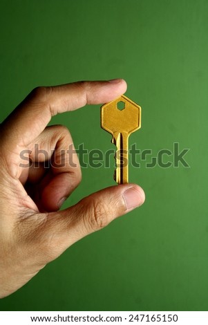 Golden key held by a hand Photo of a golden key held by a hand