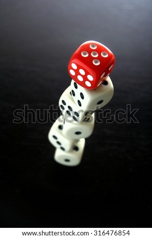 One Red game dice on top of stacked five white game dice