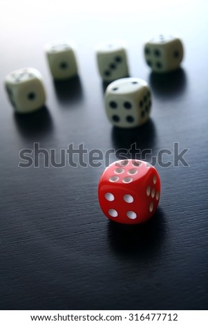 One Red game dice in front of five white game dice