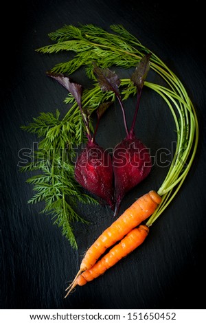 Beetroot and carrots on a black slate chalkboard