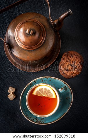 Vintage copper kettle on a slate board and tea with chocolate cookies