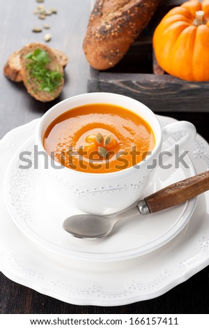 Pumpkin soup with pumpkin seeds, bread, and raw pumpkin in wooden box