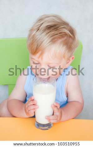 Happy smiling boy drinking milk at home