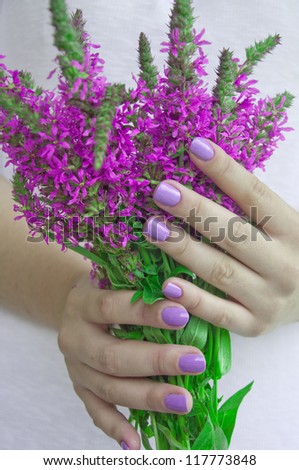Beautiful hands with manicure holding purple flower