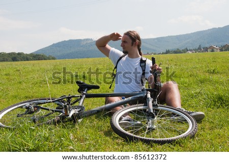 young man rest with bicycle on the meadow