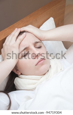 ill woman in bed touching her head
