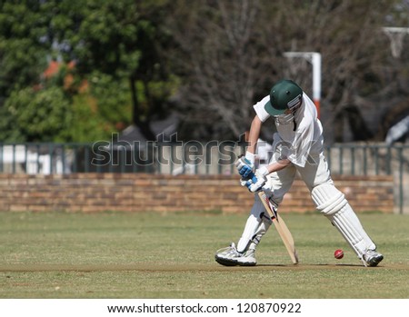 A school boy tries to block a cricket ball and prevent it from hitting his wickets. He is defensive mode but misses.