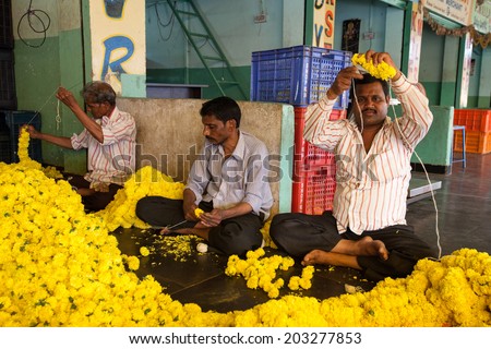 BANGALORE, INDIA - June 06: Three men creating flower ropes at KR Market in Bangalore. June 06, 2014 in Bangalore, India.