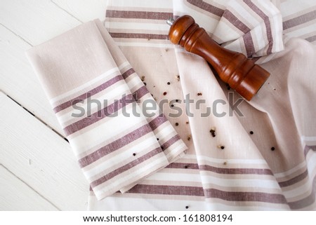 Hand towels with peppers and pepper shaker on wood background.