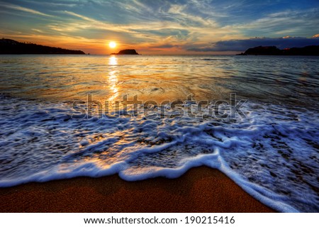 Colorful yellow and blue ocean bay sunset with sea foam
