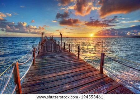 Bright ocean pier sunrise with colorful clouds over azure waters