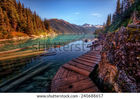 Wooden walkway along a scenic mountain lake with sunken logs