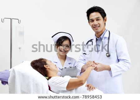 Portrait of a doctor with his co-workers talking with a patient in the background