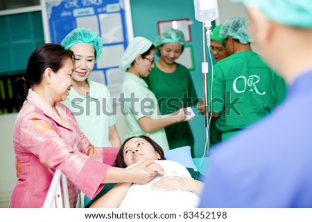 medical worker moving patient with her cousin on hospital trolley to operating room
