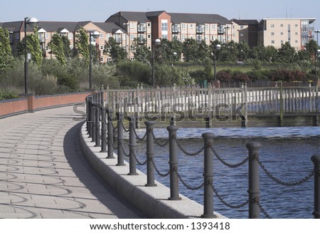 view of lakeside development showing lake,walled path with chain railing, bridge and properties